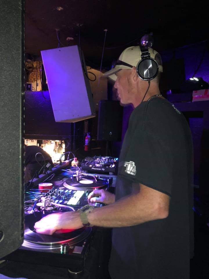 DJ Natural Nate® on Pioneer DJ decks under purple club lighting